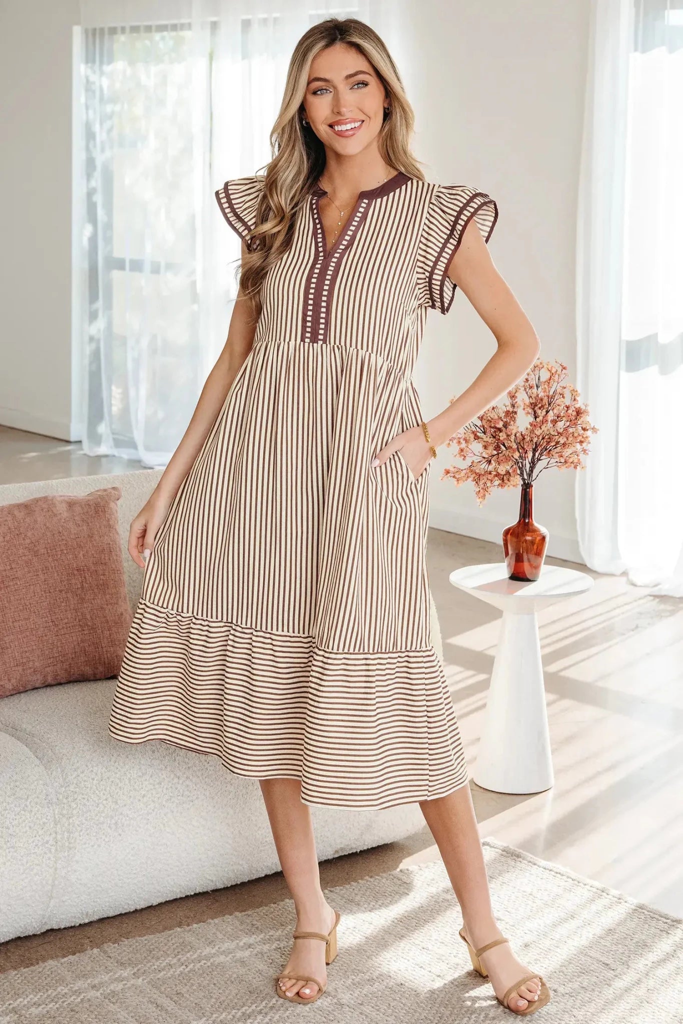 Woman wearing a striped dress in a bright living room.