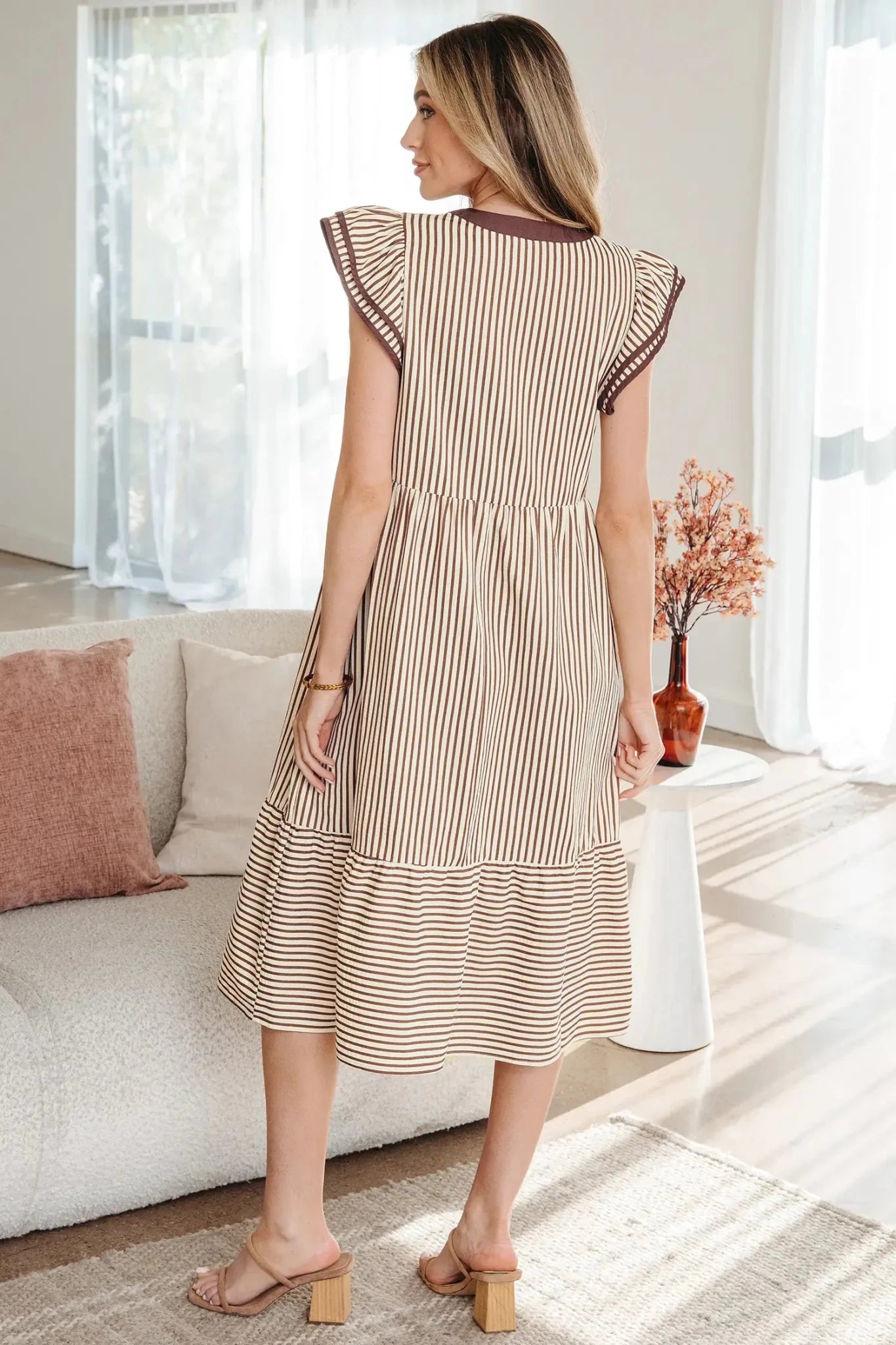 Woman wearing a striped dress in a bright living room.