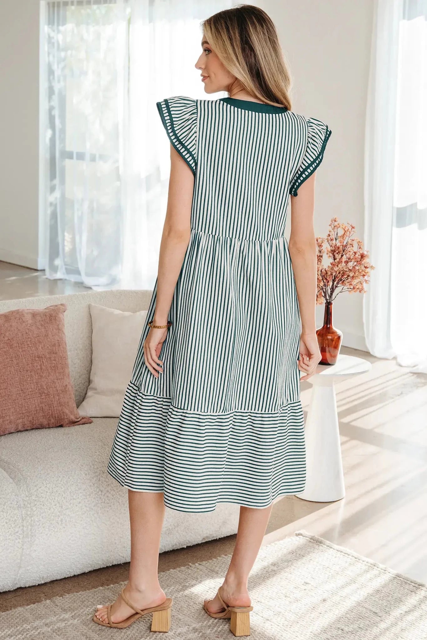 Woman wearing a green and white striped dress in a living room.