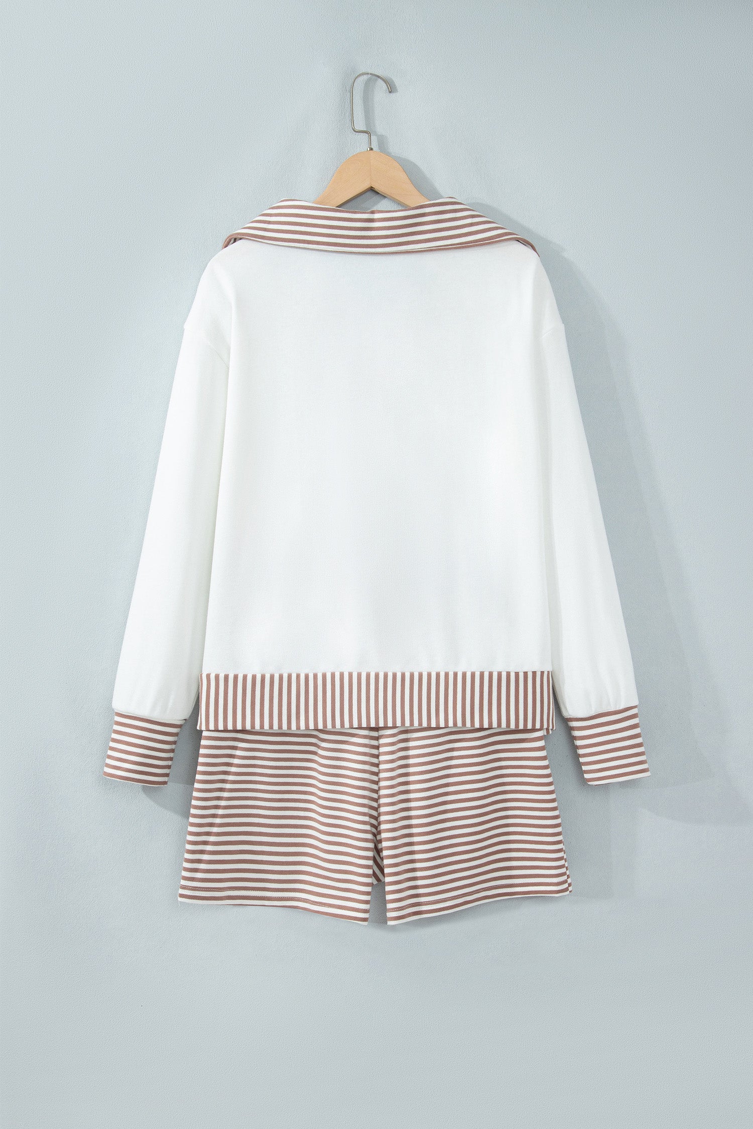 White half zip top and striped shorts set on a hanger, back view