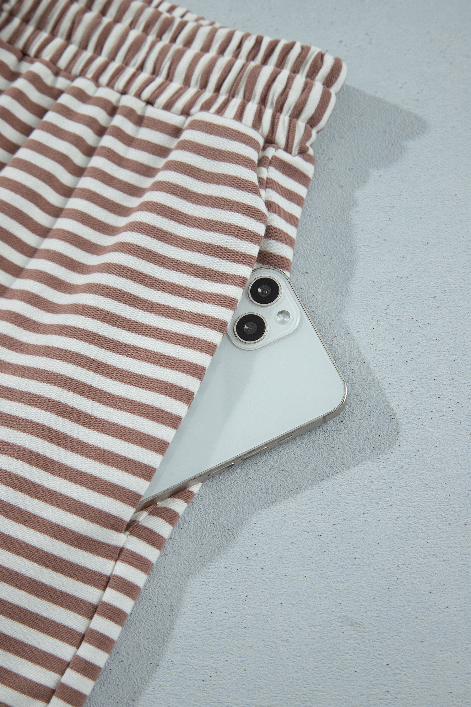 Khaki striped shorts side pocket holding a phone