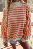 Oversized orange striped mock neck top with ribbed cream cuffs, close front view