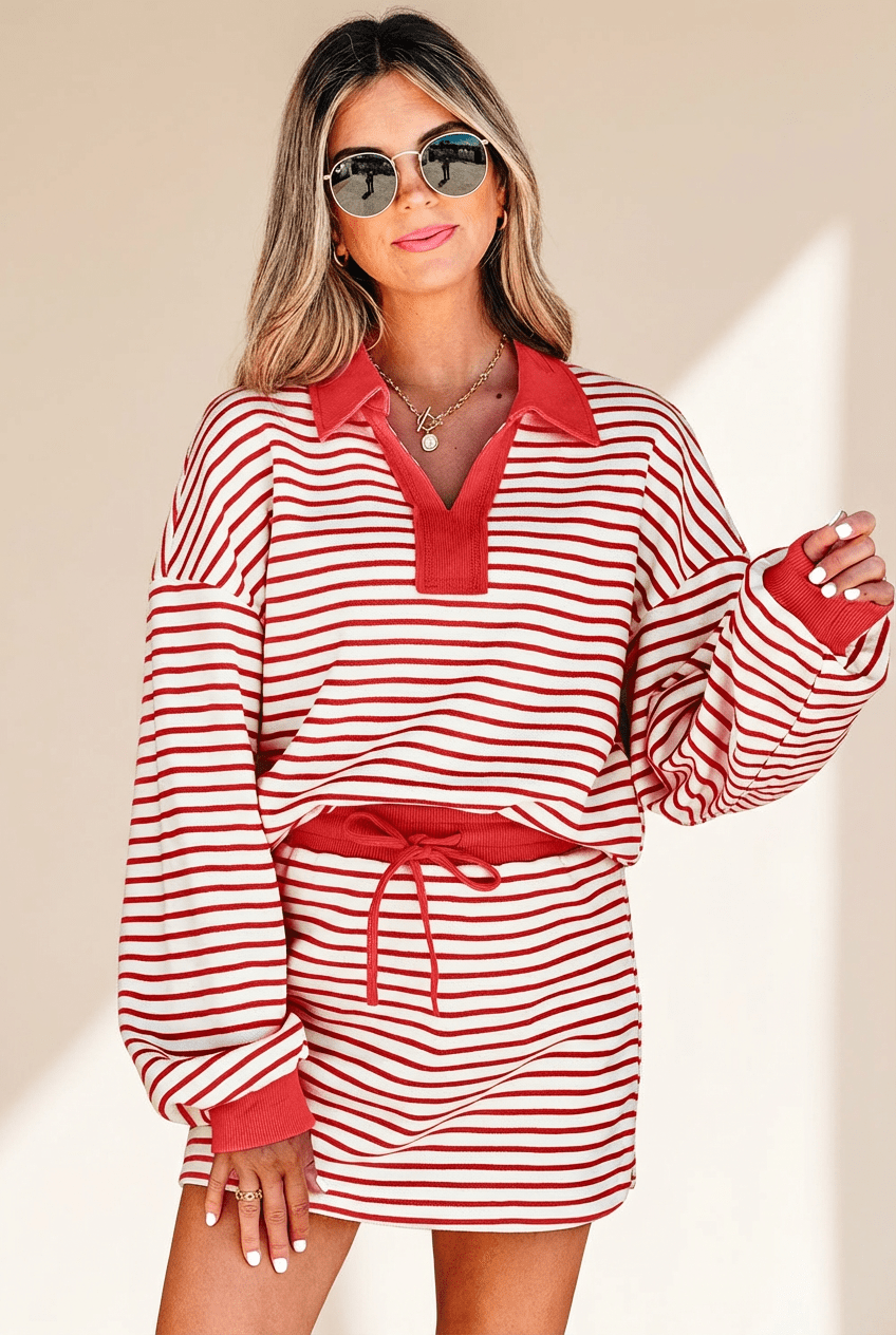 Woman wearing a red and white striped dress with a belt against a beige background