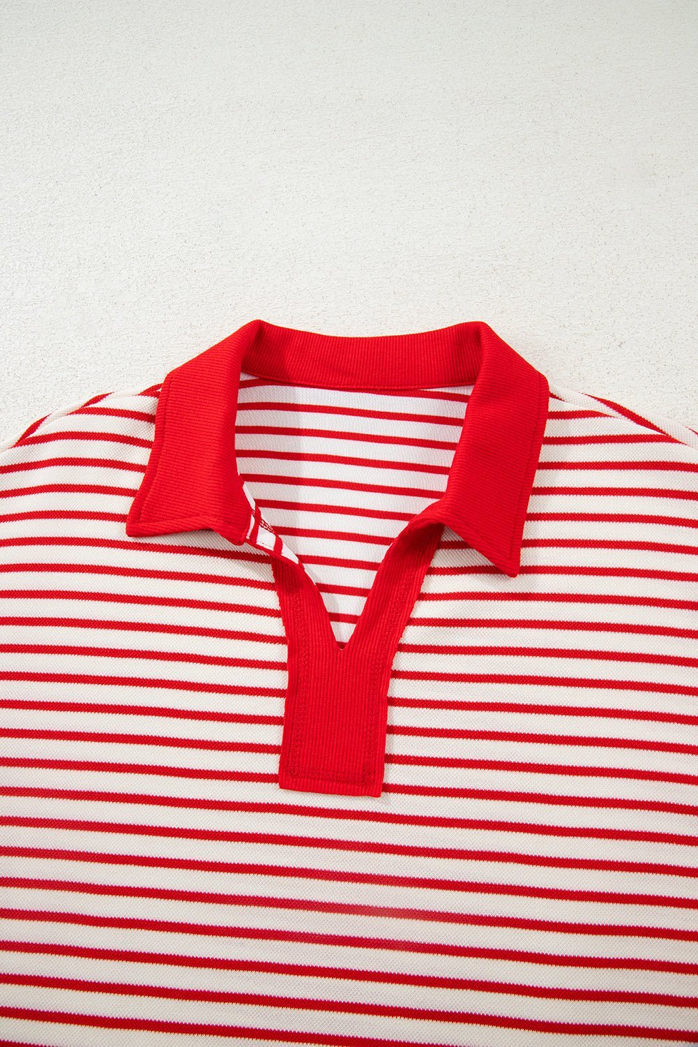 Red and white striped polo shirt with a red collar on a light gray background