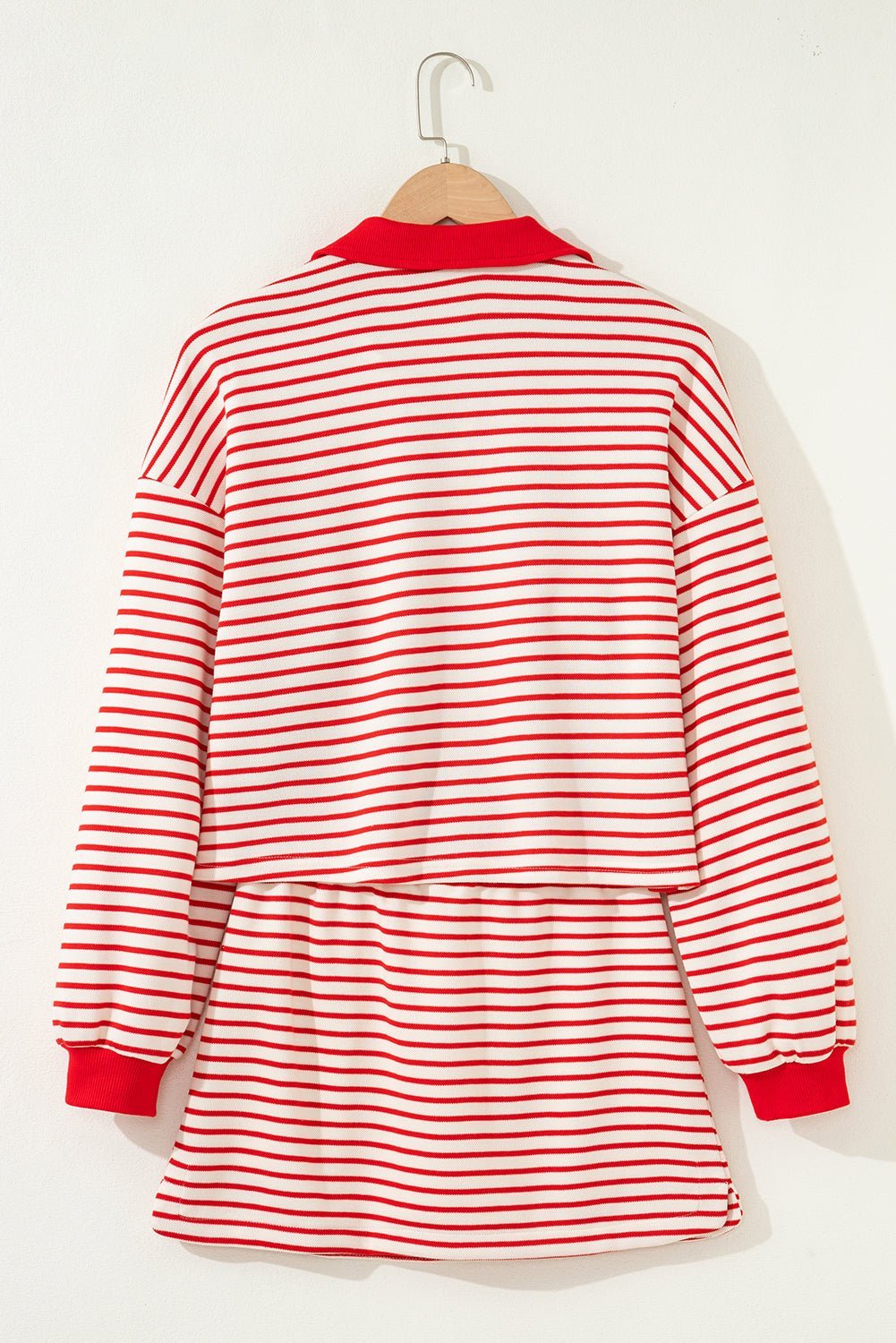 Red and white striped dress on a hanger against a white background
