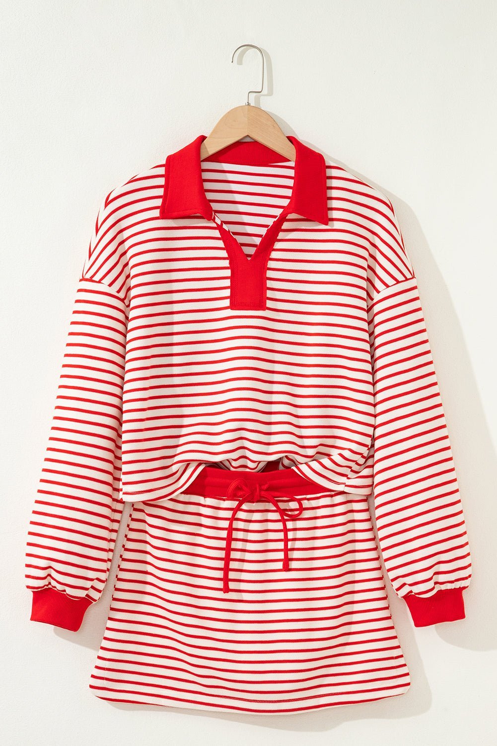 Red and white striped dress with long sleeves on a hanger against a white background