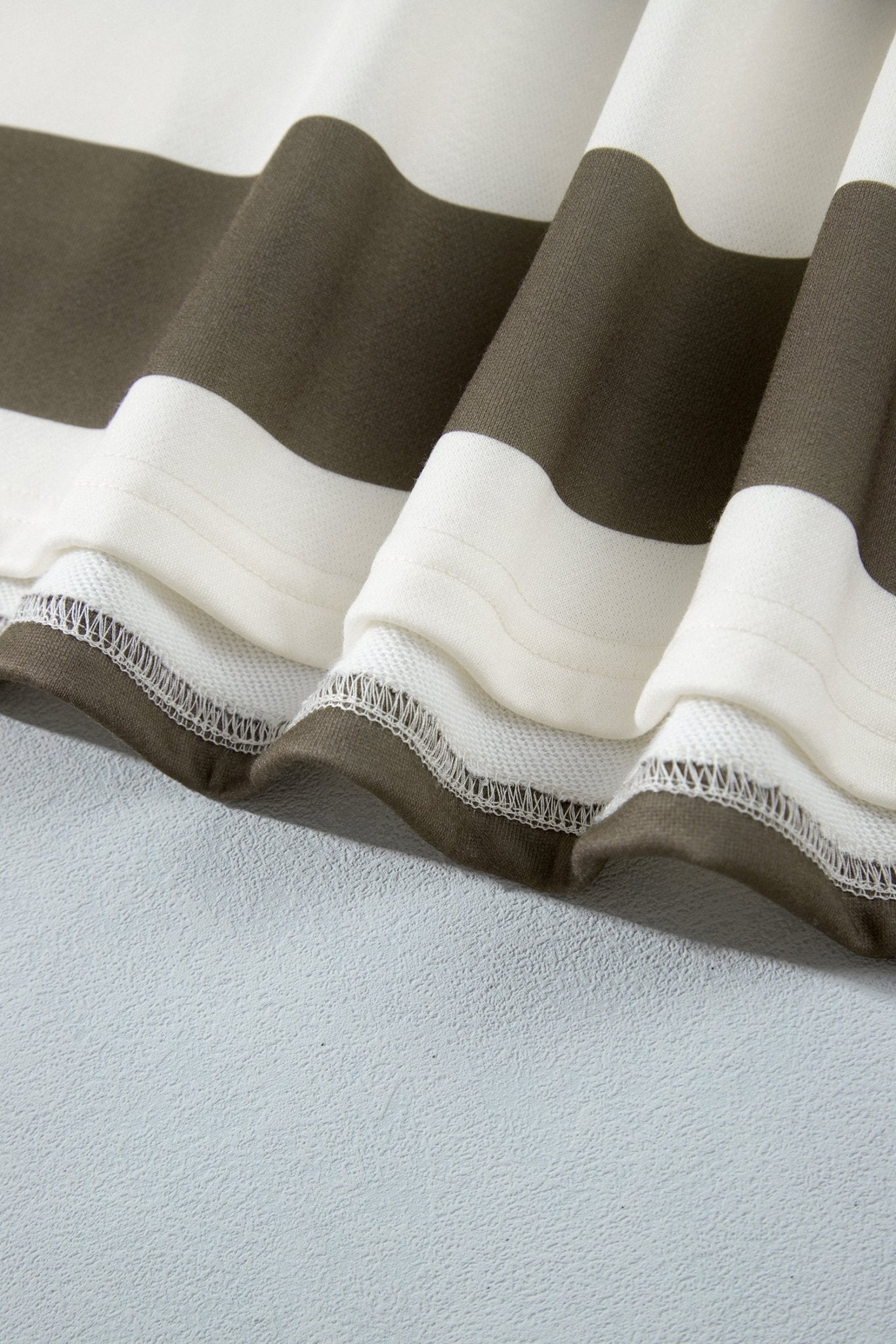 Close-up of wide dark brown and off-white striped fabric with textured hem.