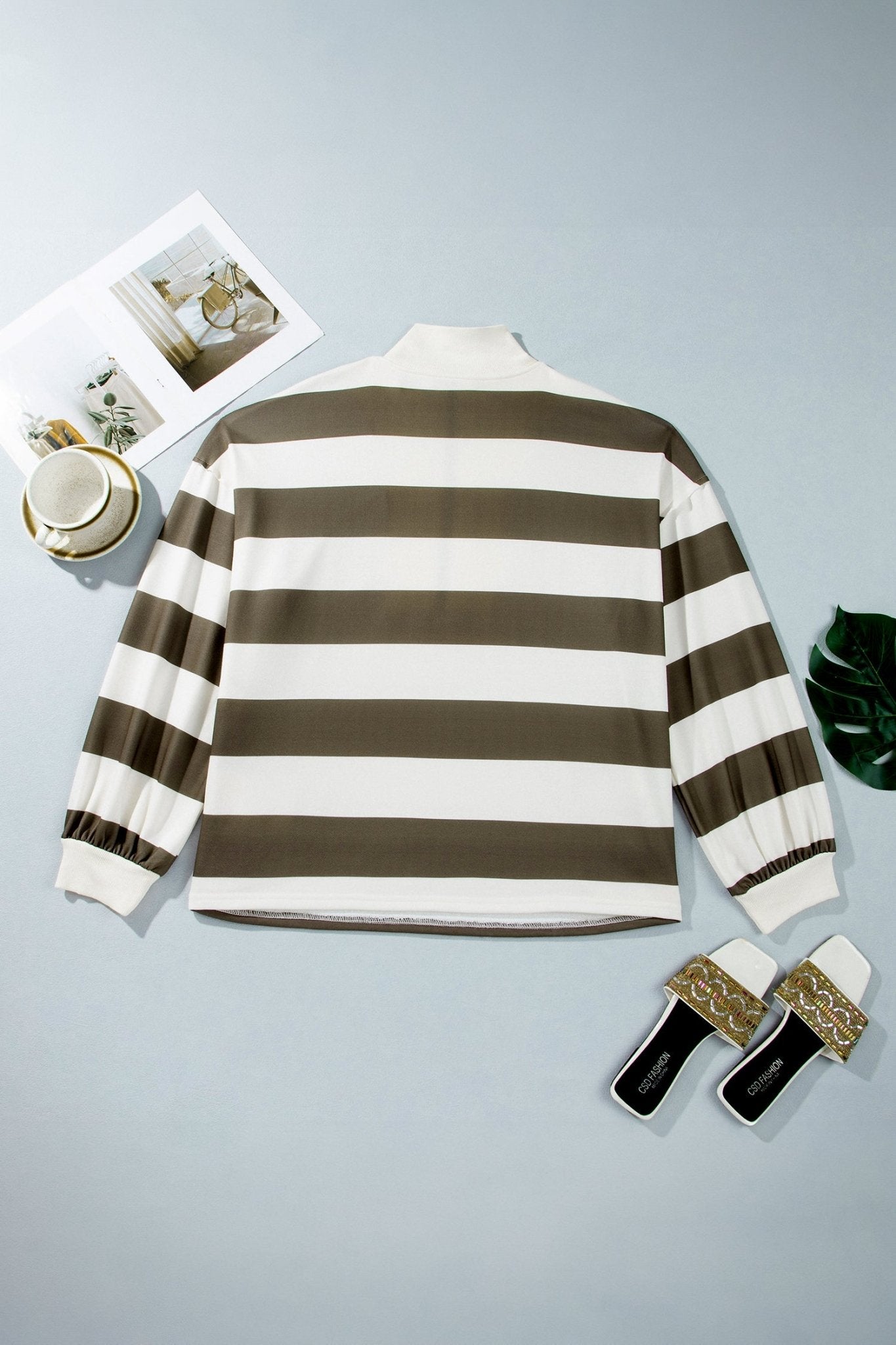 Brown/white striped mock-neck flat lay with cup, magazine, shoes on blue-gray.