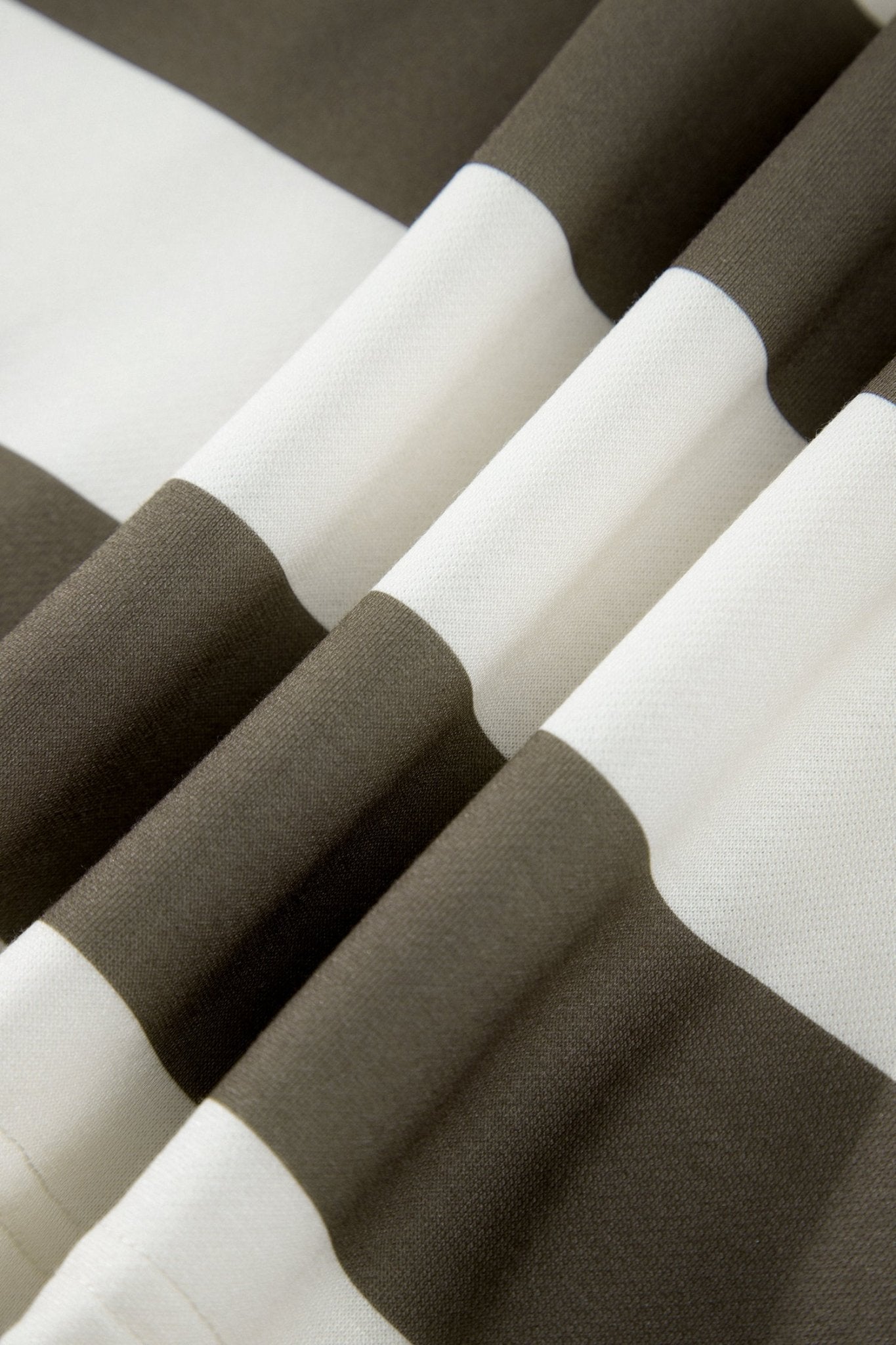 Close-up of soft-folded fabric with wide white and dark taupe-brown stripes.