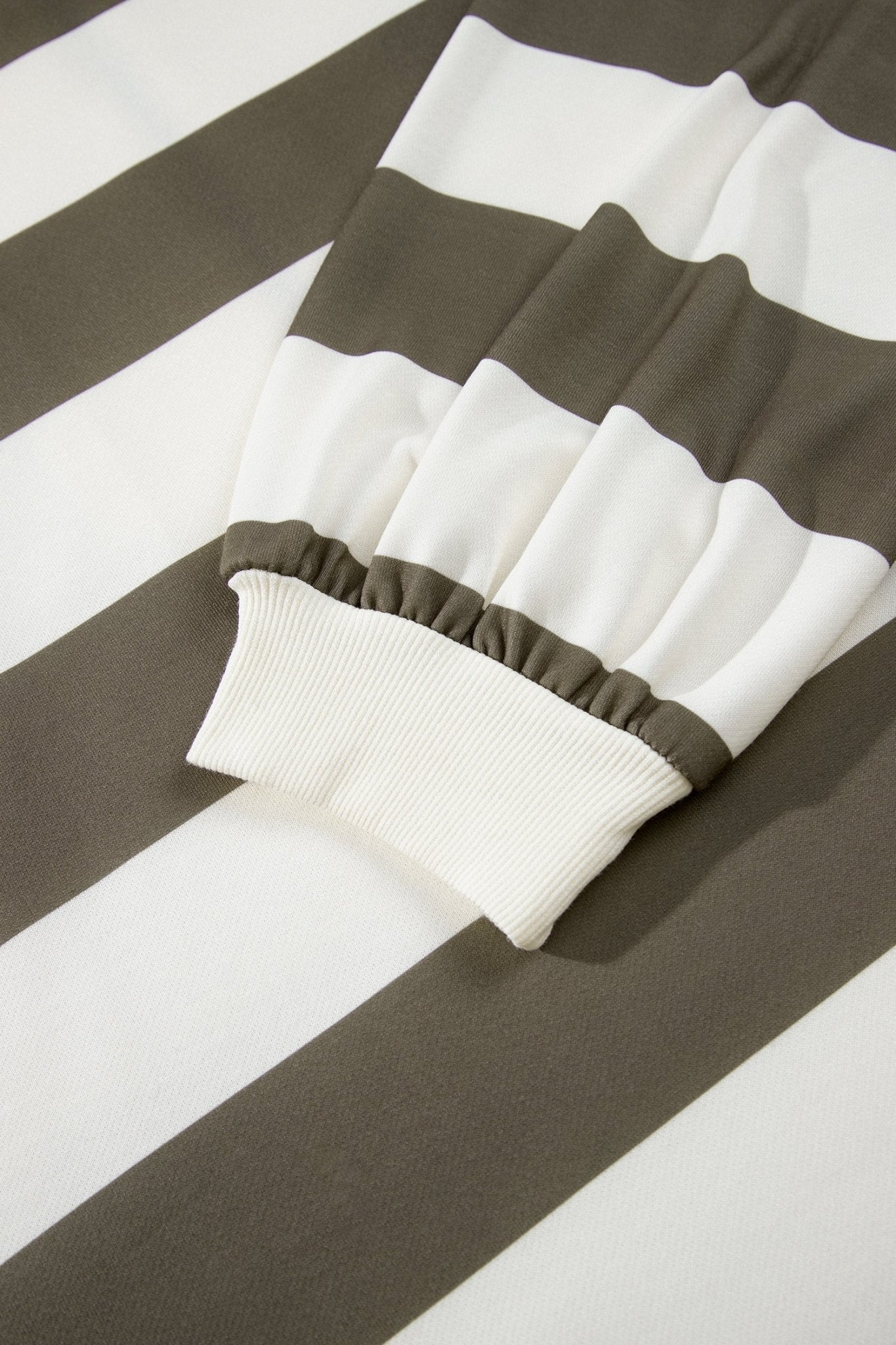 Close-up of wide brown and white striped garment with ribbed white cuff.