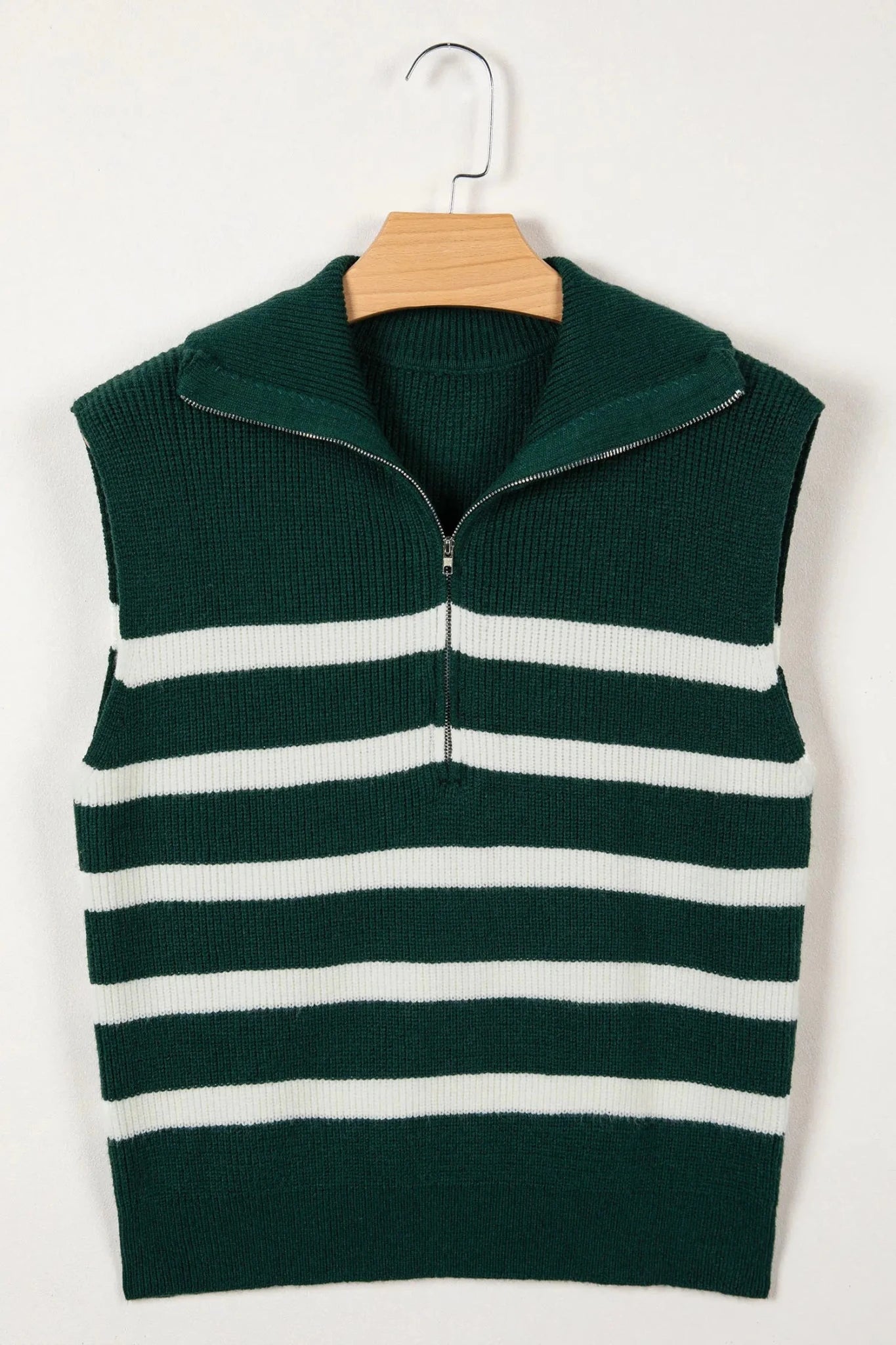 Green and white striped sweater vest on a hanger against a white background