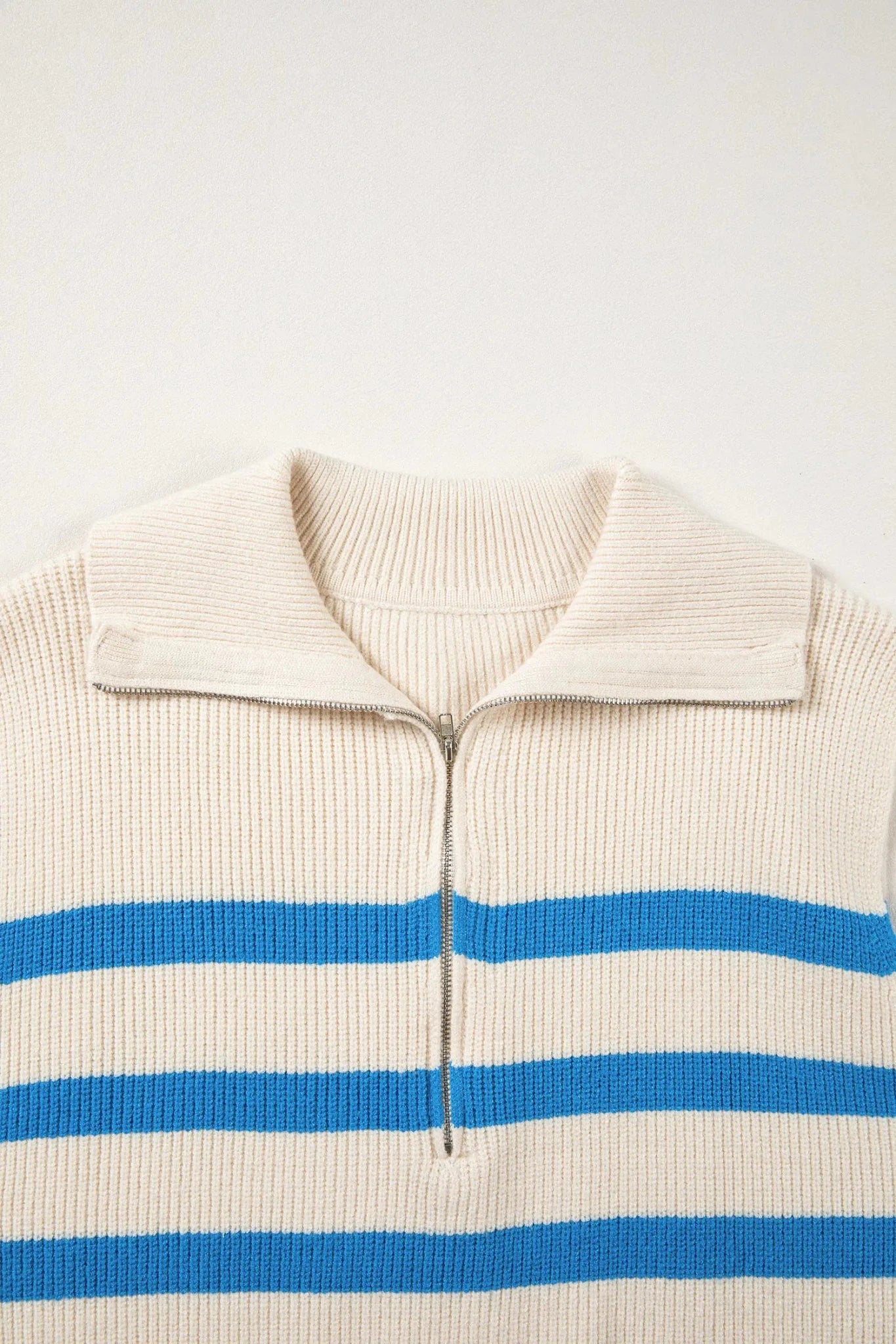 Beige sweater with blue stripes on a light beige background