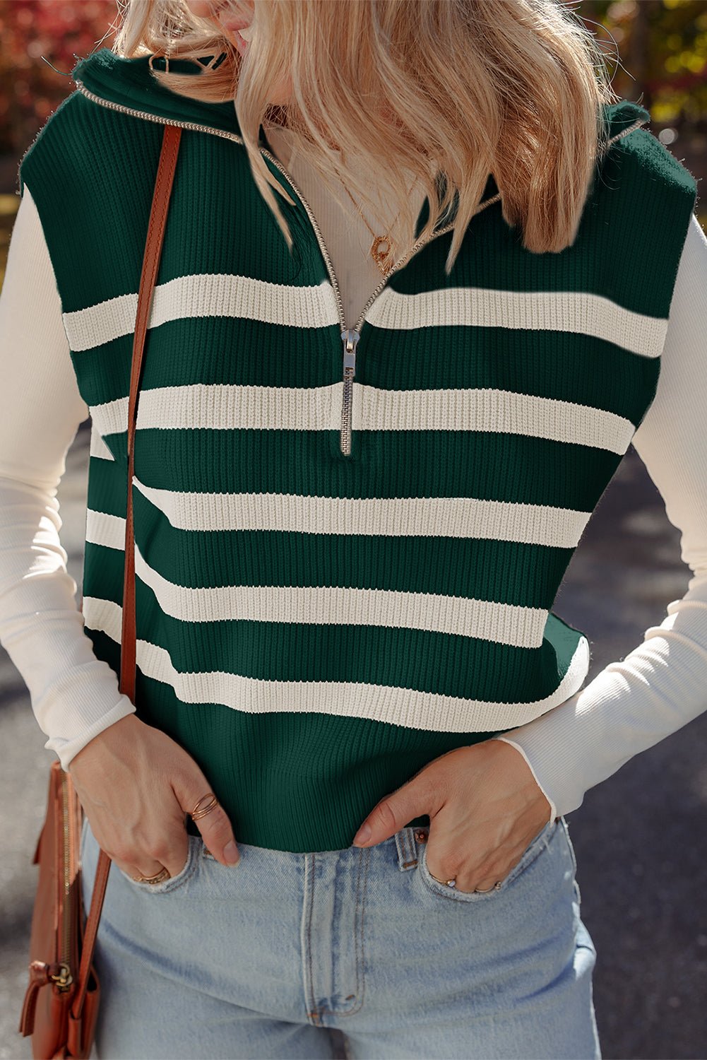 Person wearing a green and white striped sweater vest with a blurred background