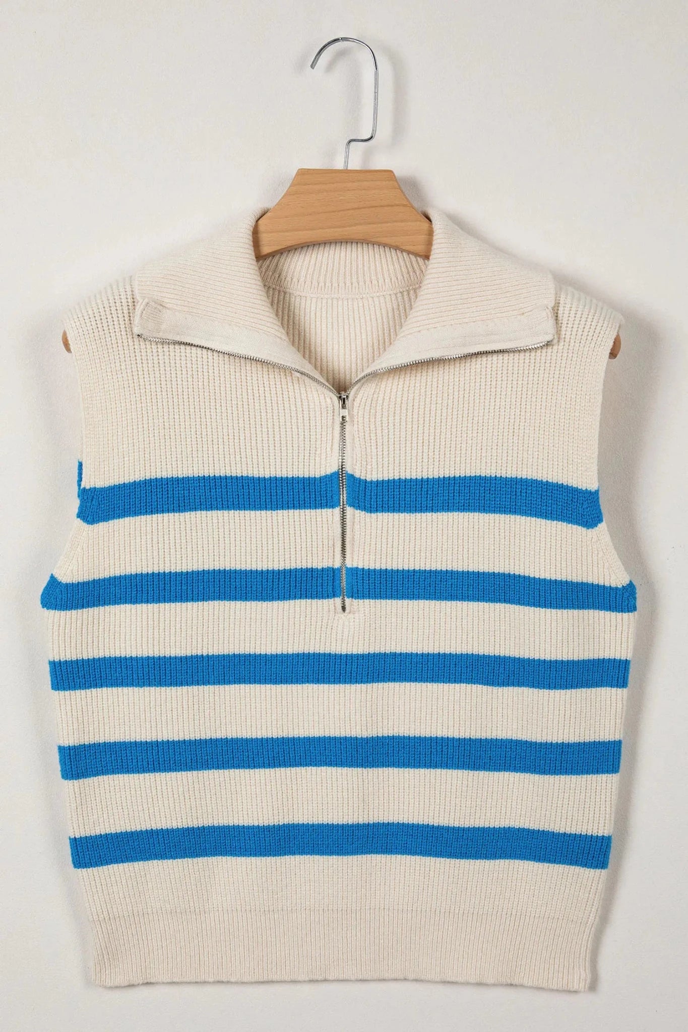 Beige and blue striped sweater vest on a hanger against a white background