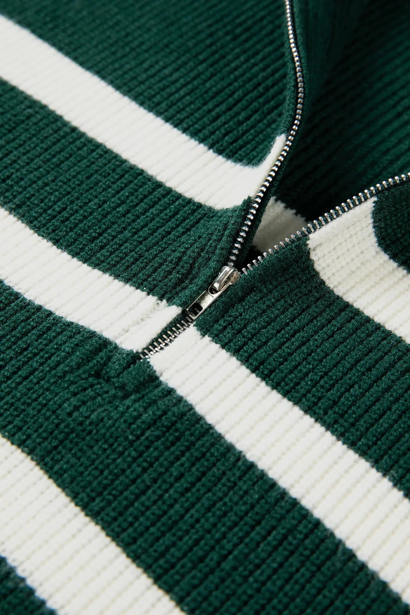 Close-up of a green and white striped sweater with a zipper.