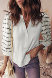 Person wearing a white blouse, striped cardigan, and purple pants with a beige handbag.