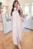 Woman taking a mirror selfie in a living room wearing a long white and gray striped dress.