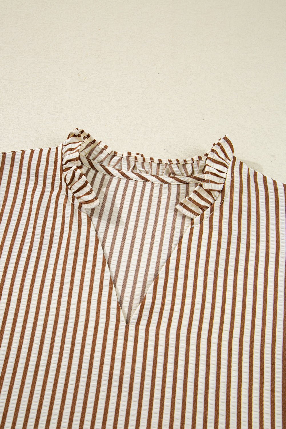 Striped shirt with ruffled collar on a beige background