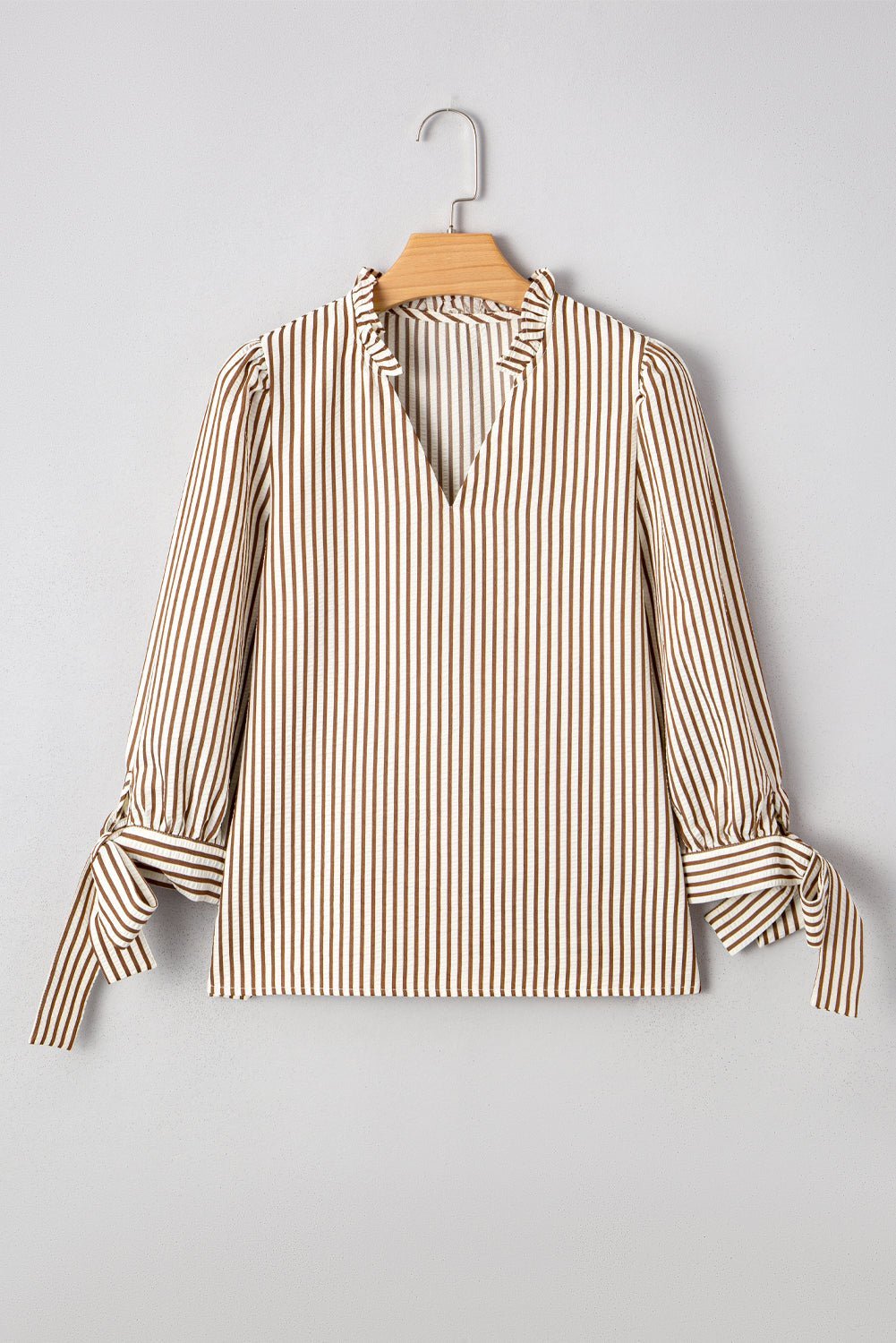 Striped blouse on a hanger against a gray background