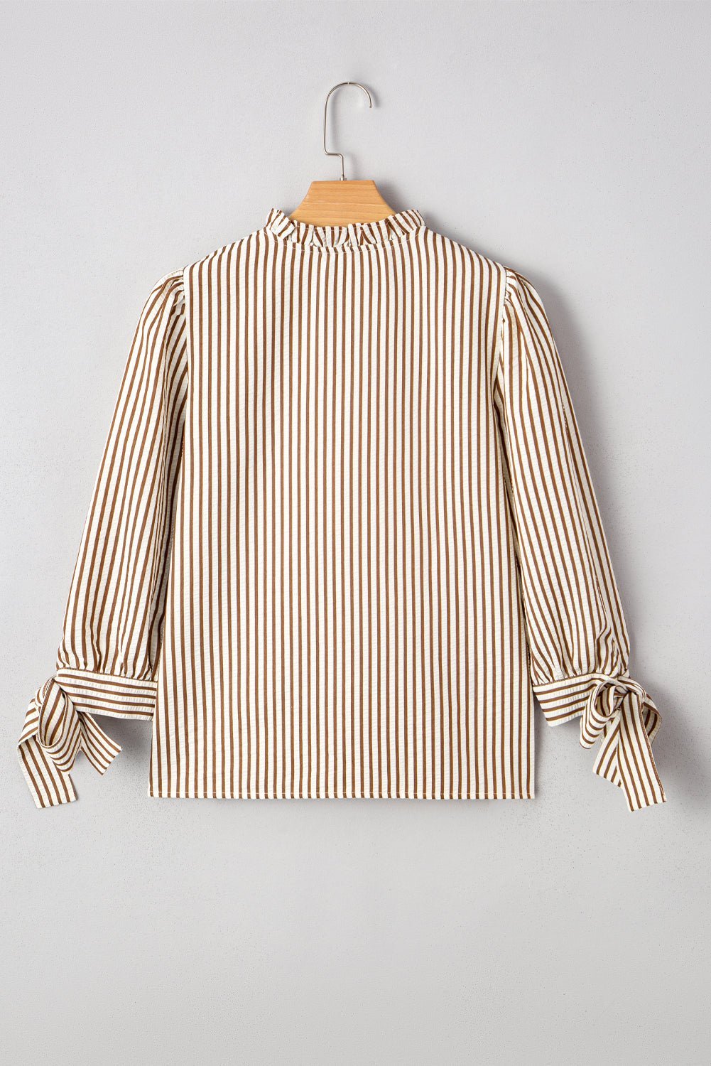 Striped blouse on a hanger against a gray background