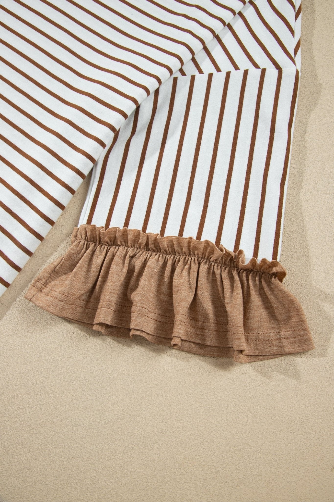 A striped blanket with vertical brown stripes, white base, and taupe ruffle trim.