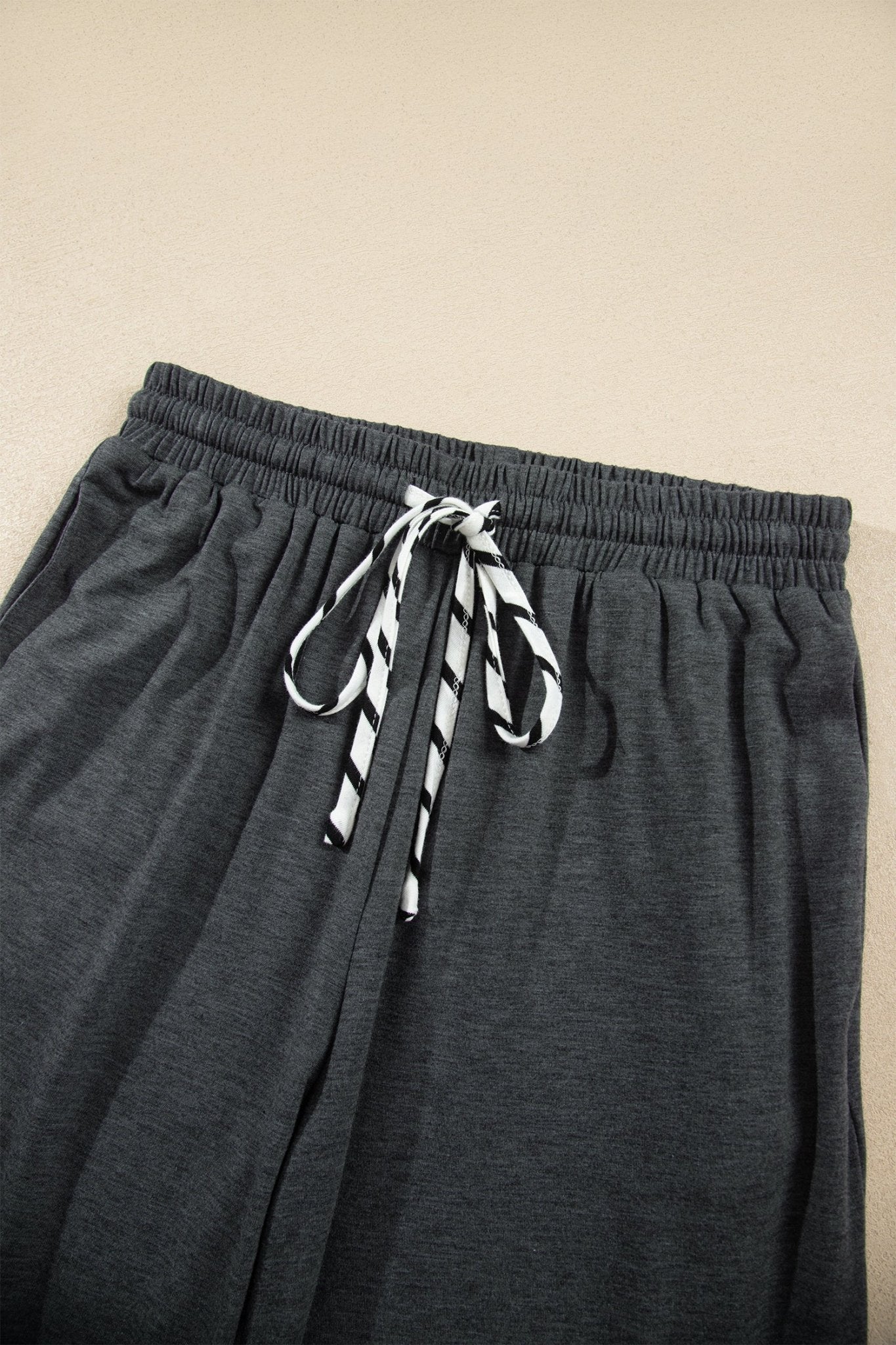 Dark gray heather lounge pants with elastic waistband and black-and-white striped drawstring.