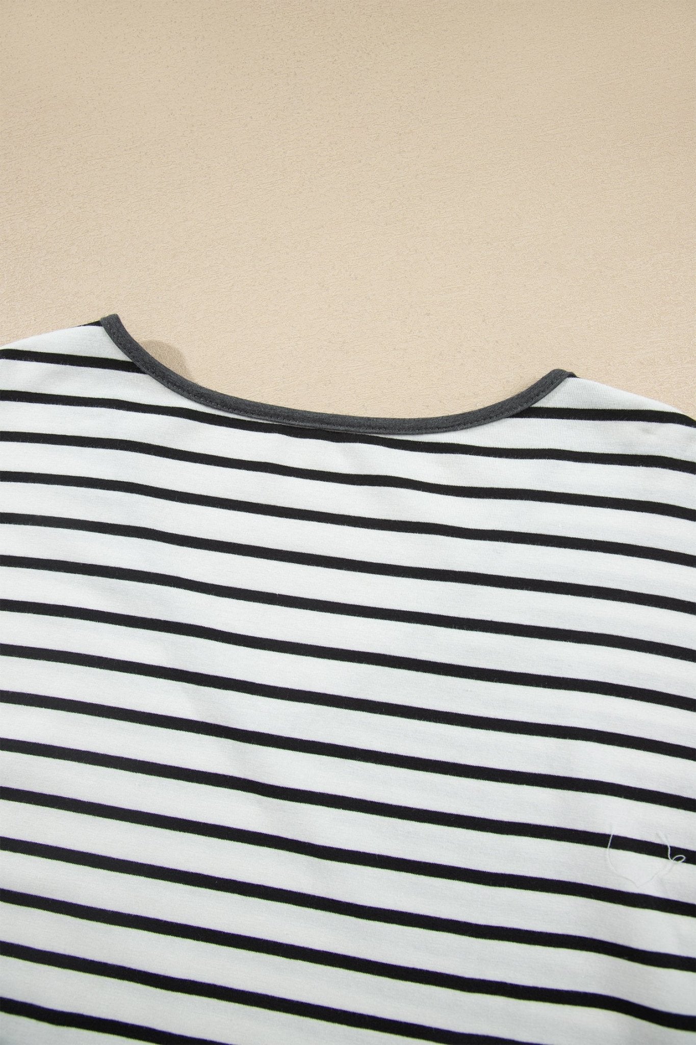 Close-up of a white striped top with thin black stripes and dark gray crew neck trim.