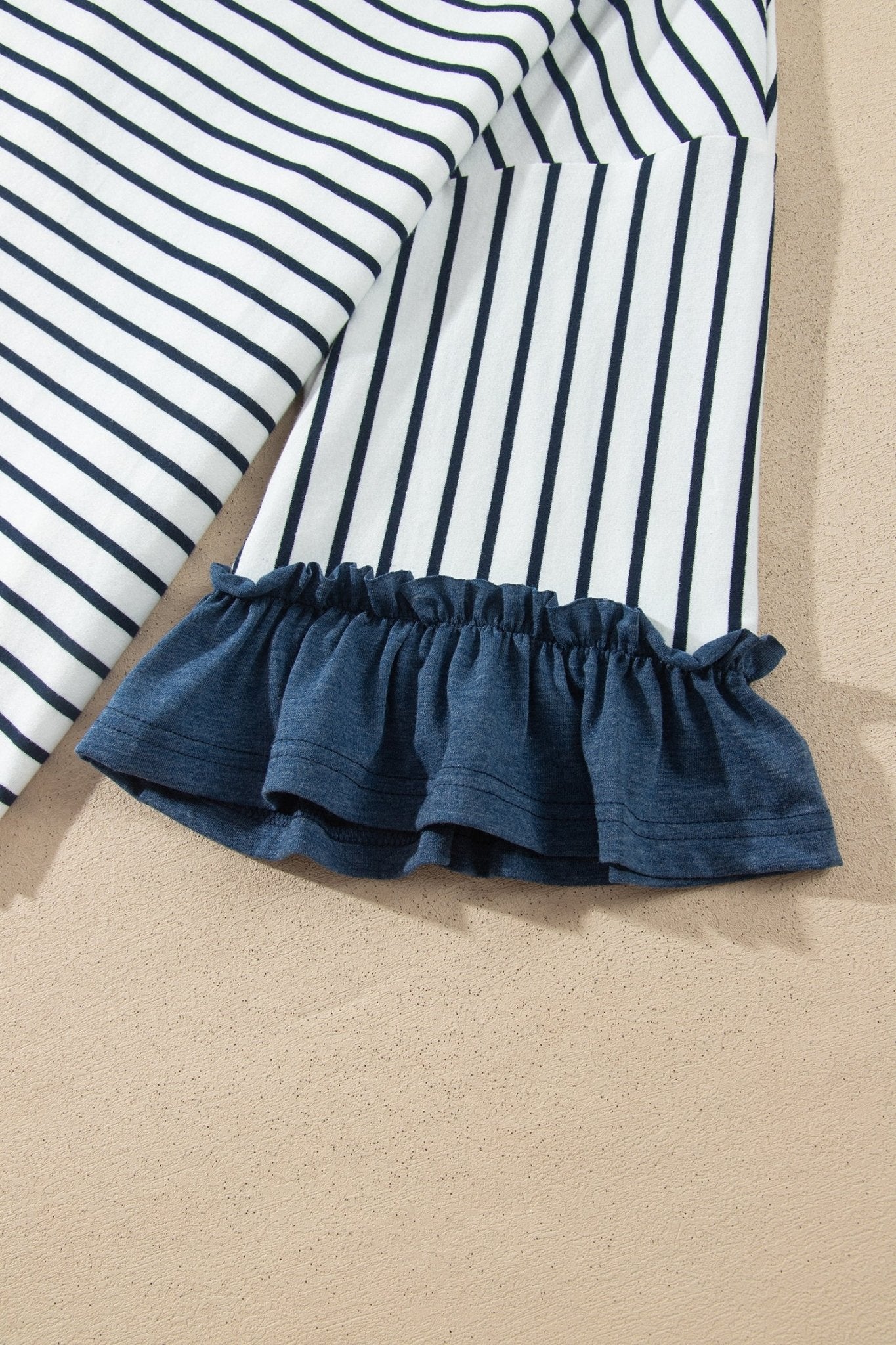 Close-up of navy and white striped fabric with a gathered dark blue ruffle hem.