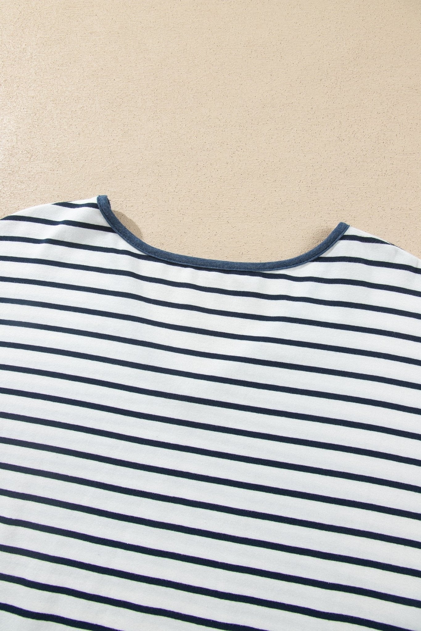 Close-up of a striped top with navy horizontal stripes on white fabric and a back neckline.
