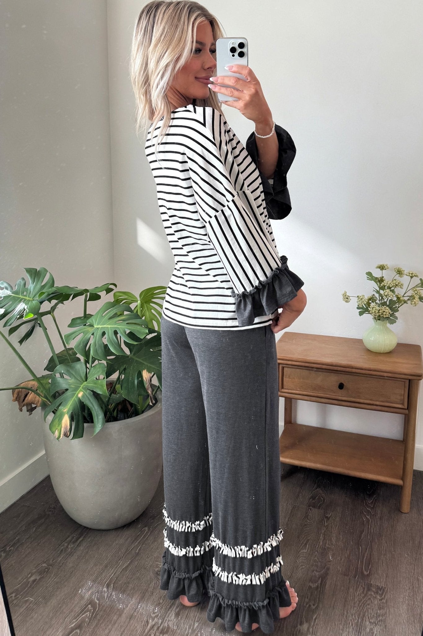 Woman in a black and white striped top with dark gray wide-leg ruffle-trim pants.