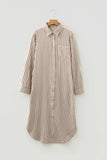 A long-sleeve button-front shirt dress with vertical brown and beige stripes, featuring a single chest pocket, shown hanging on a wooden hanger against a light gray background.