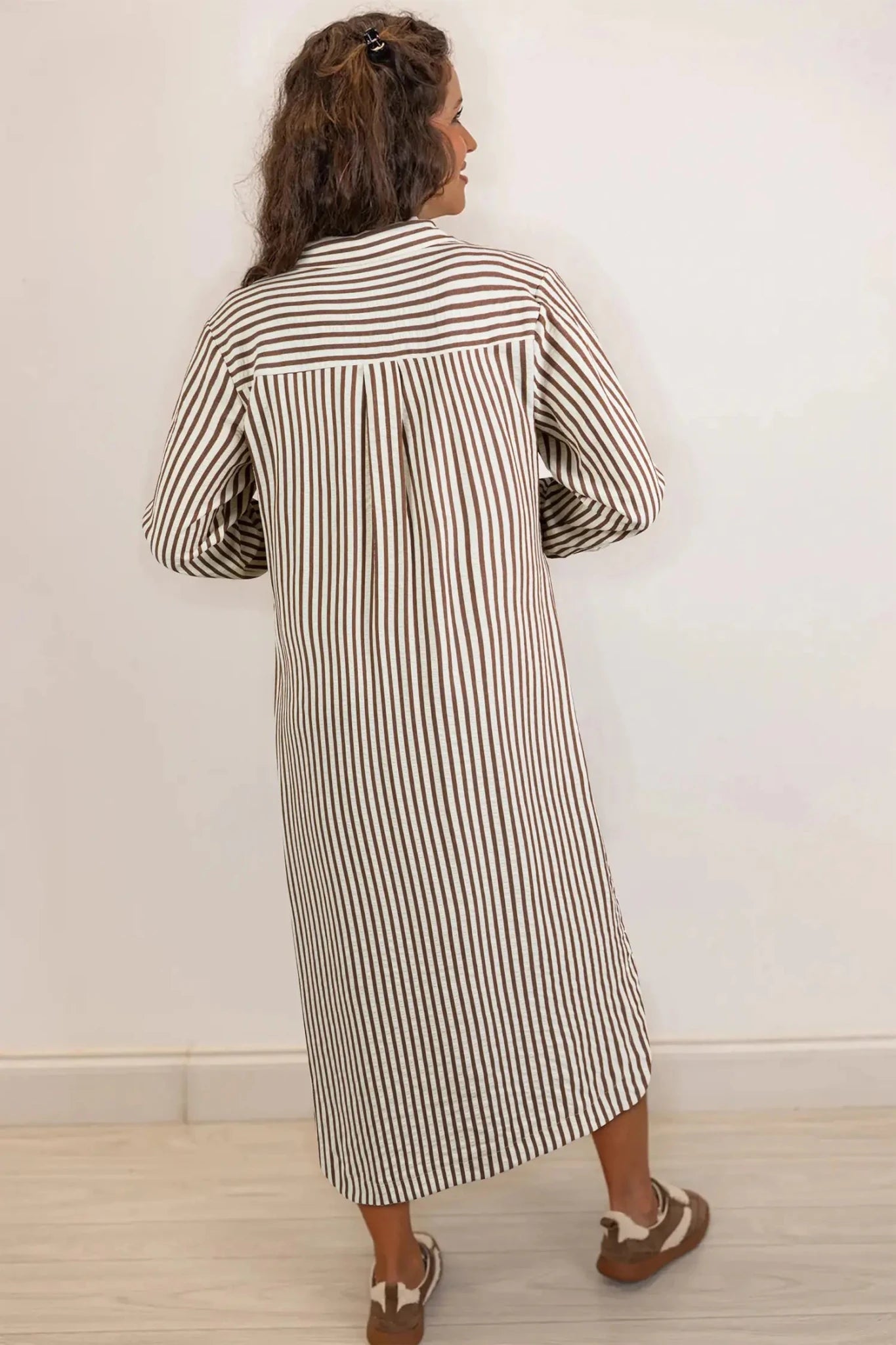 Woman wearing a long black and white striped dress against a plain background