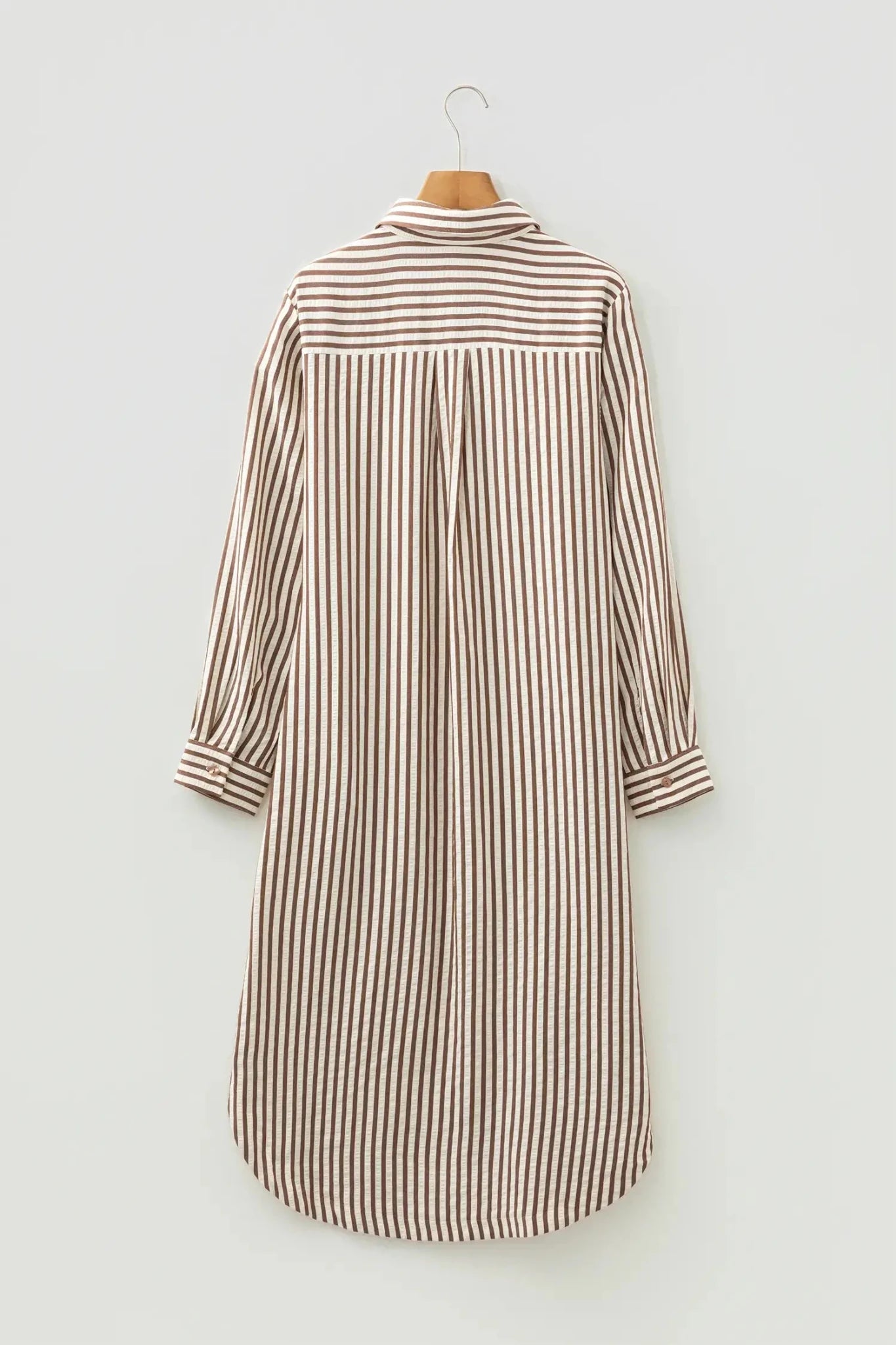 Striped shirt dress hanging on a white wall
