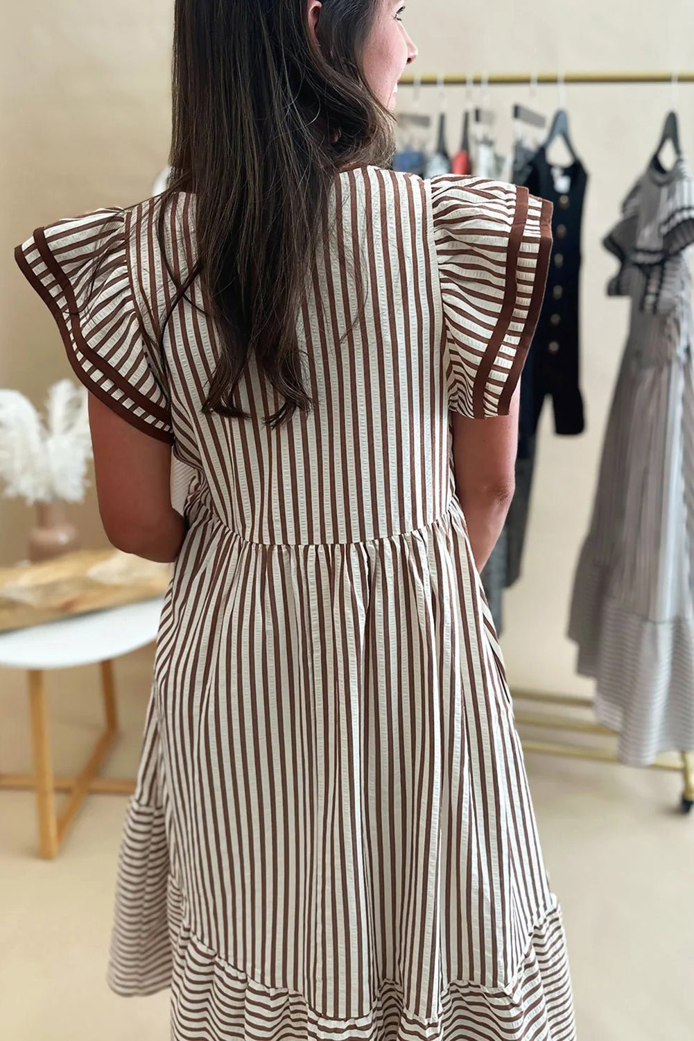 Woman wearing a striped dress in a clothing store.