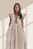 Woman wearing a striped dress standing against a neutral background