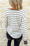Person wearing a black and white striped sweater against a stone wall.