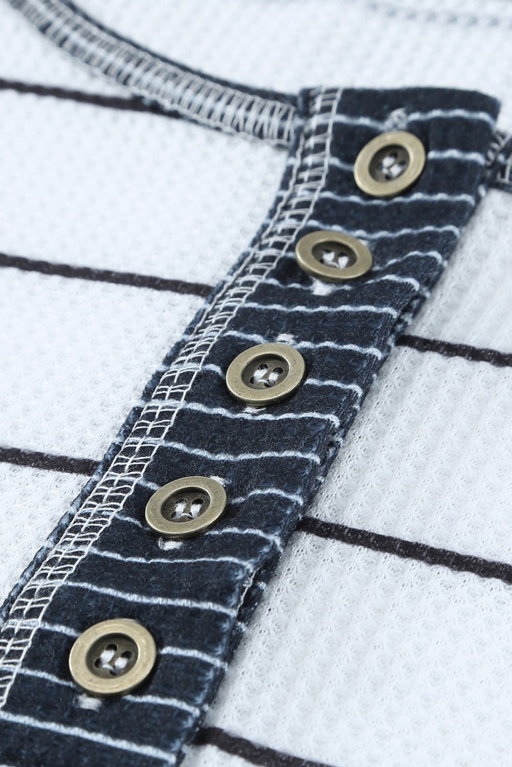 Close-up of a denim fabric with metal buttons on a white background