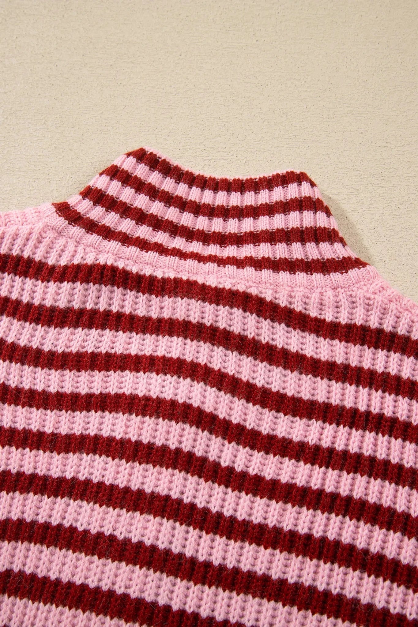 Close-up of light pink and dark red striped knit turtleneck sweater.