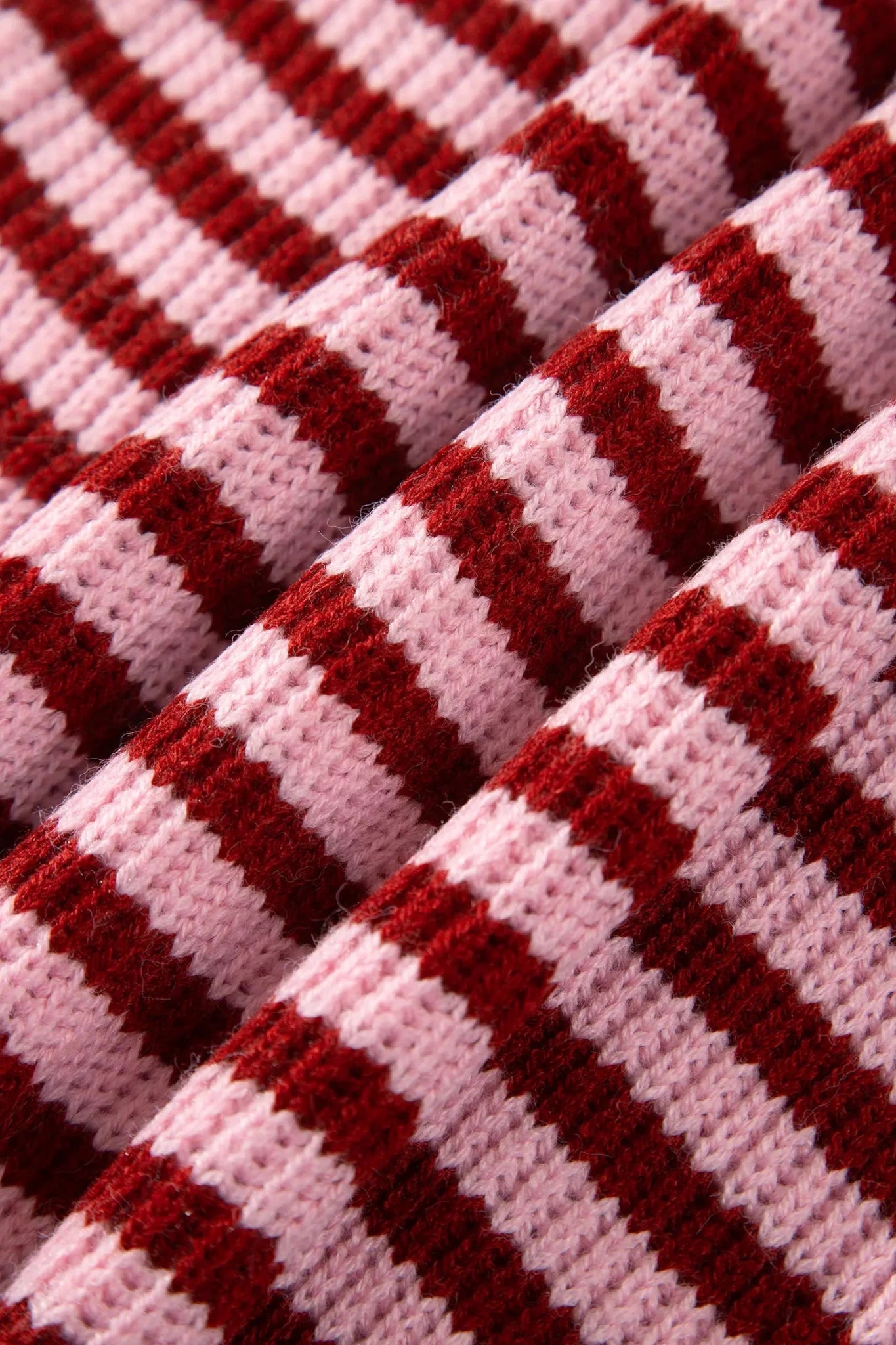 Close-up of light pink and deep burgundy red striped knit fabric.
