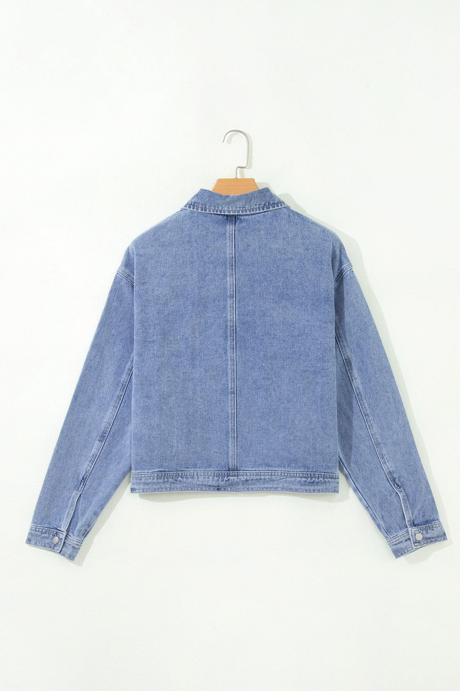 Light blue cropped denim jacket on a hanger, back view