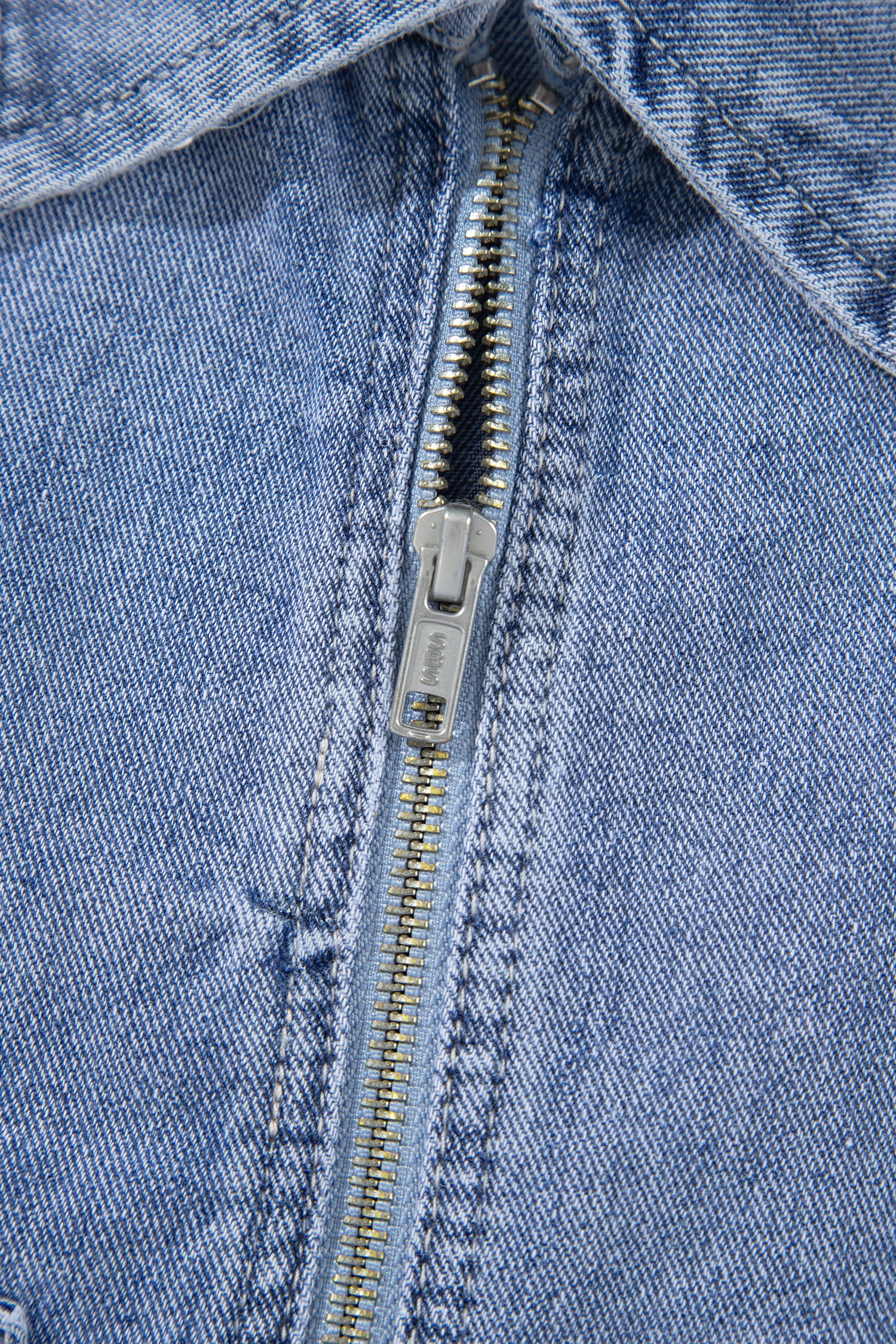 Light blue denim jacket metal front zipper close-up