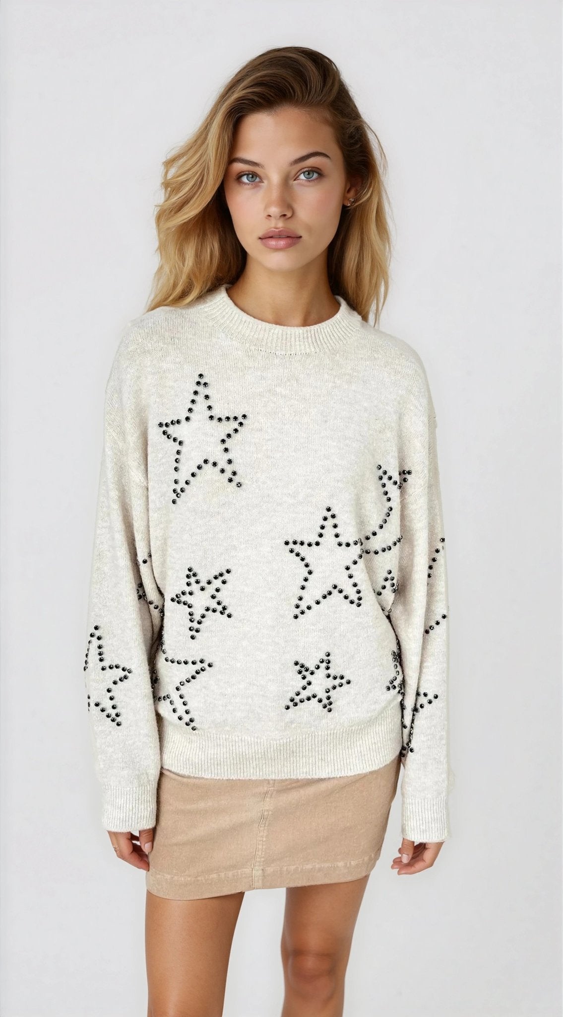 Woman wearing a cream sweater with star patterns on a white background