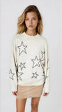 Woman wearing a cream sweater with star patterns on a white background