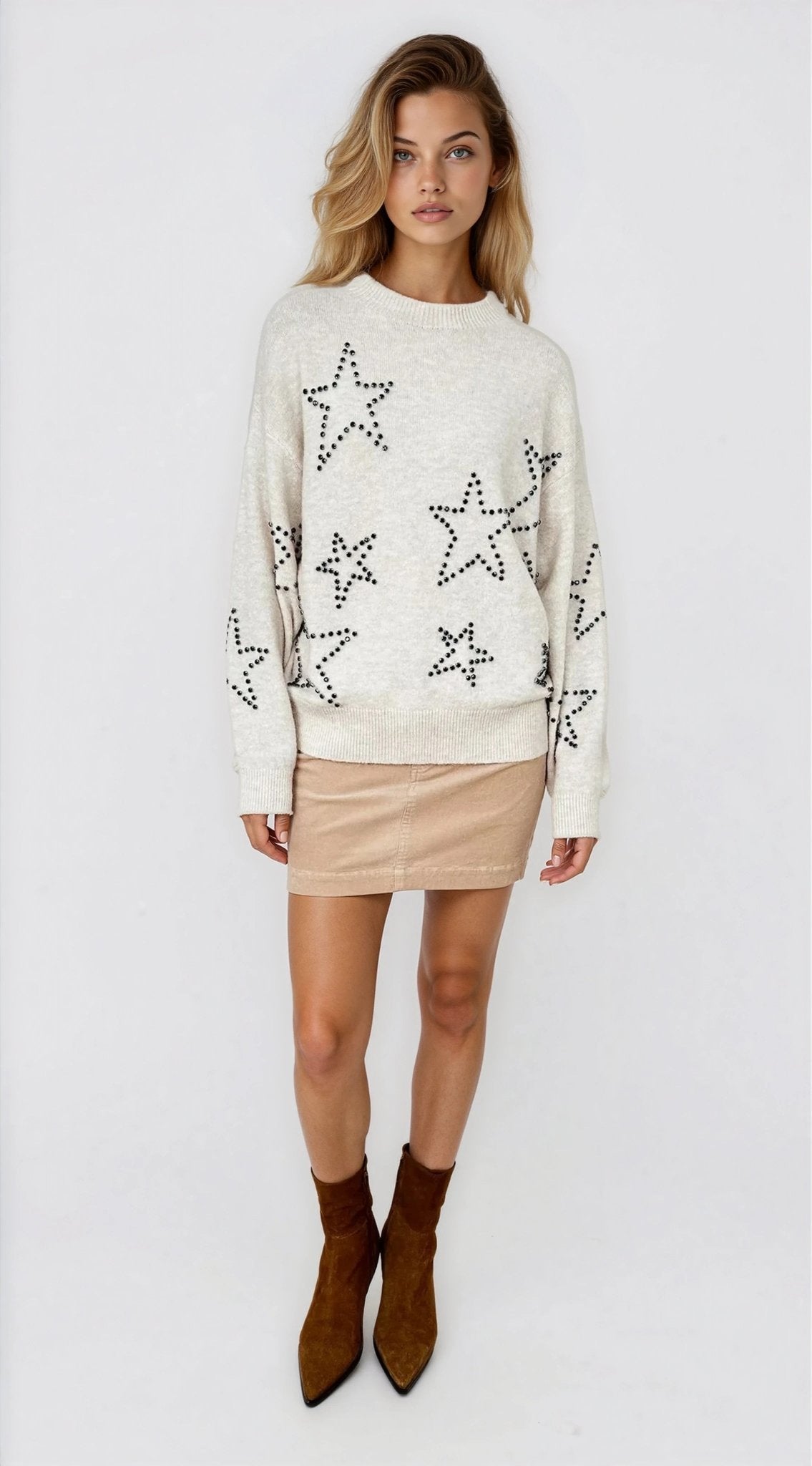 Woman wearing a cream sweater with star patterns on a white background