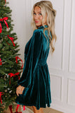 Side view of teal velvet balloon sleeve mini dress by a Christmas tree