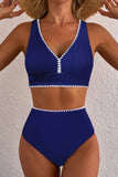Woman wearing a blue bikini with white trim against a plain background
