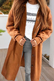 Person wearing a long brown coat over a white sweater with black patterns, standing on a wooden deck.