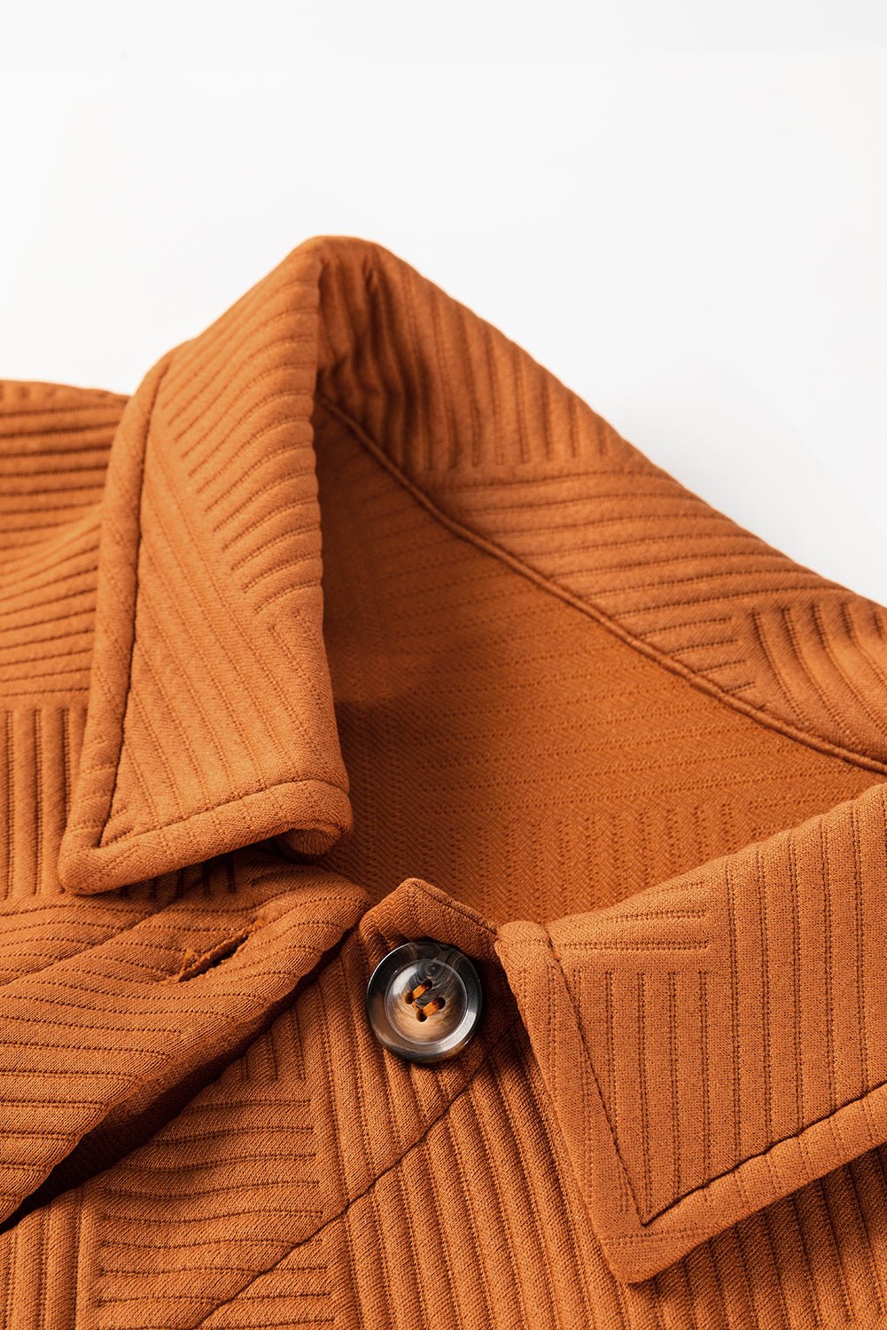 Close-up of a brown textured jacket with a button on a white background