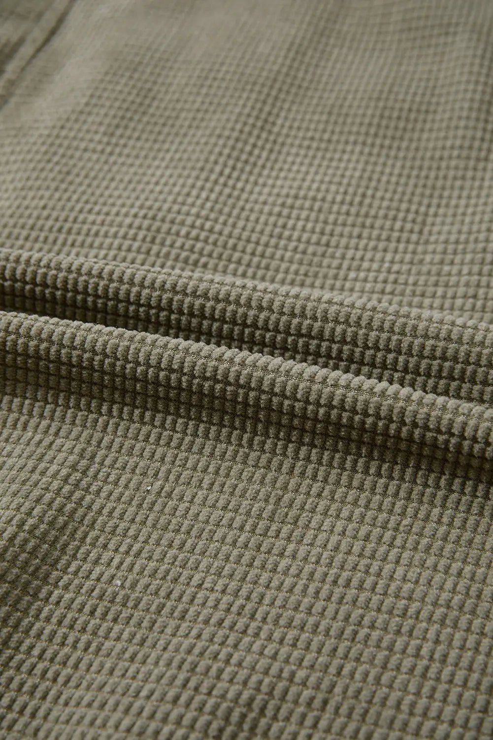 Close-up of textured green fabric with a waffle pattern.