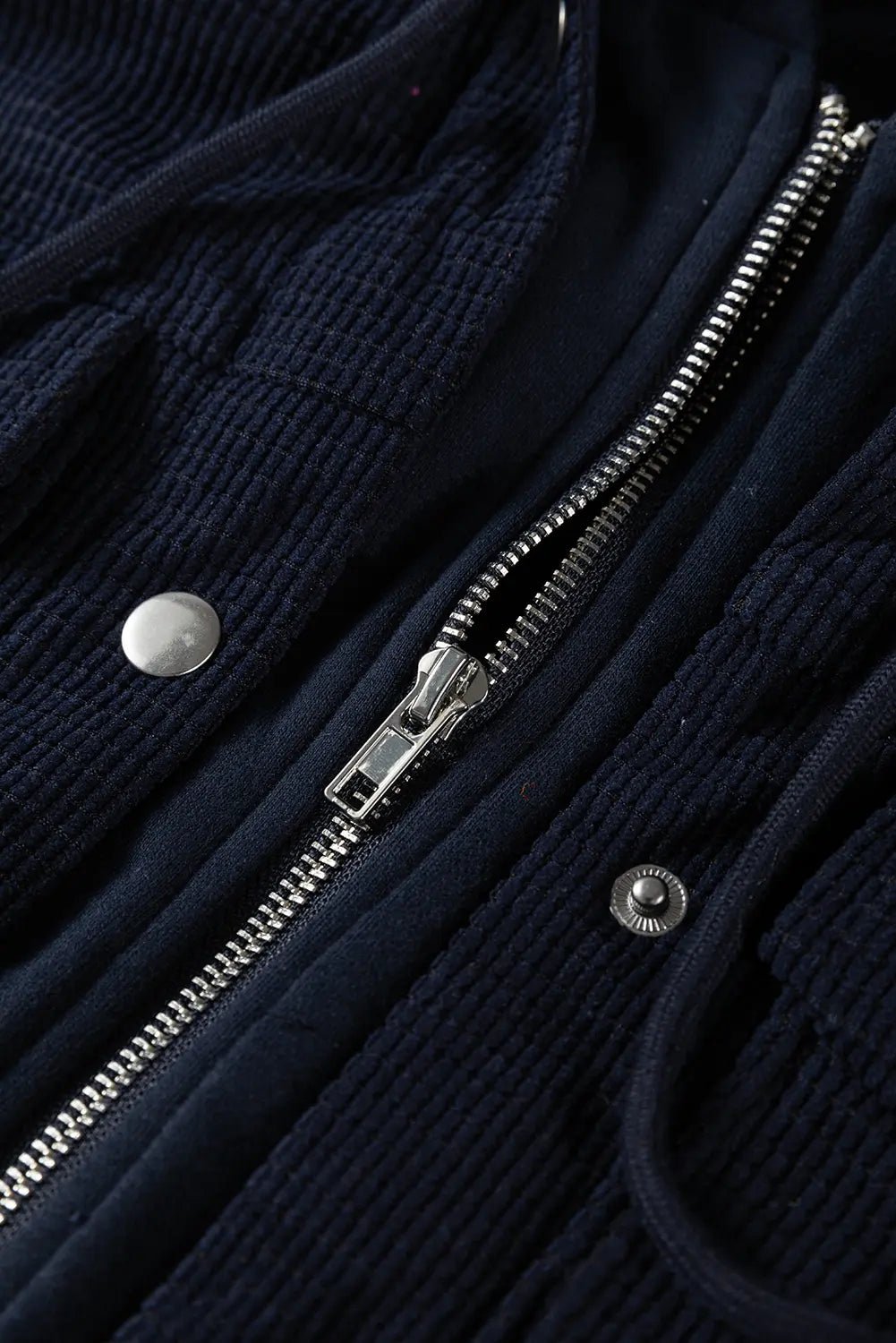 Close-up of a navy blue jacket with a zipper and buttons.